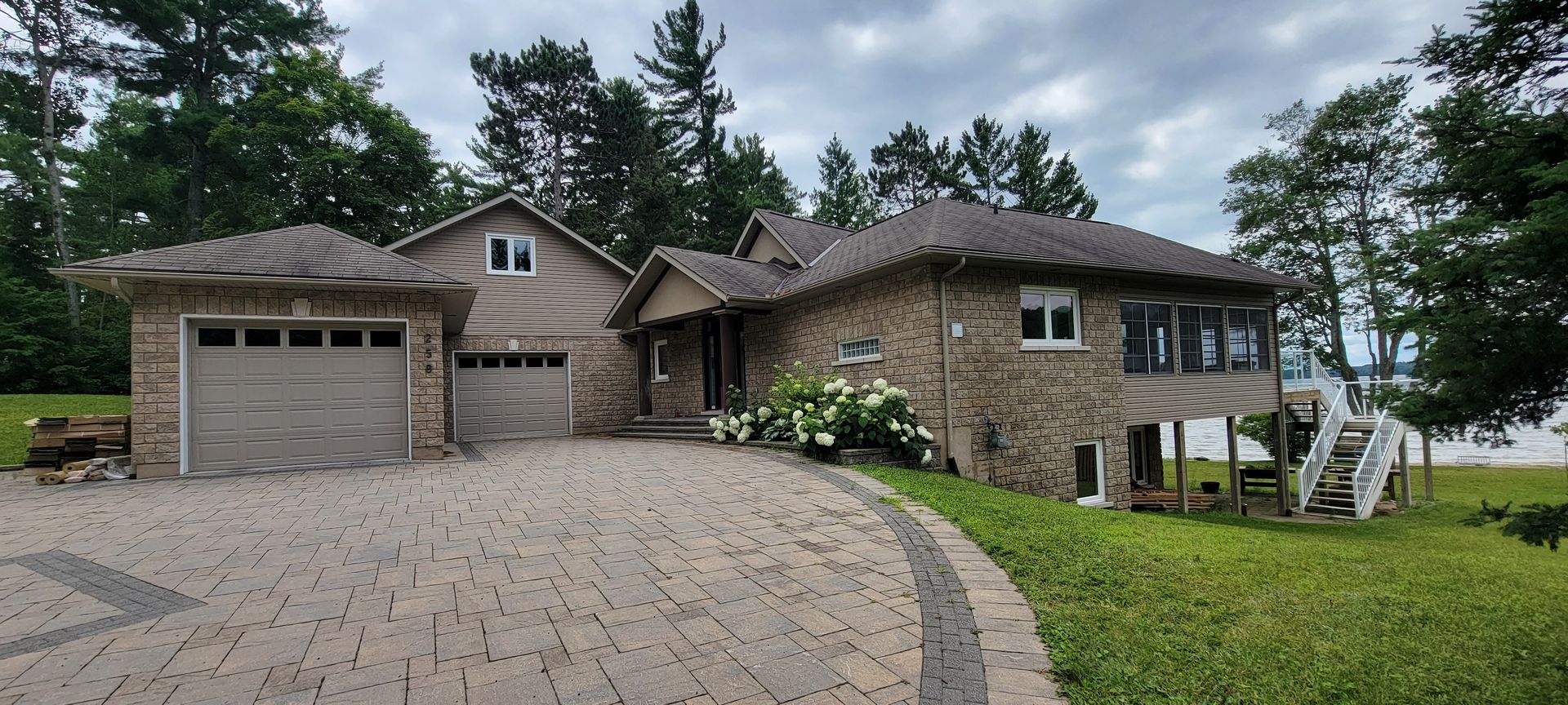 A large house with a driveway leading to it is surrounded by trees.