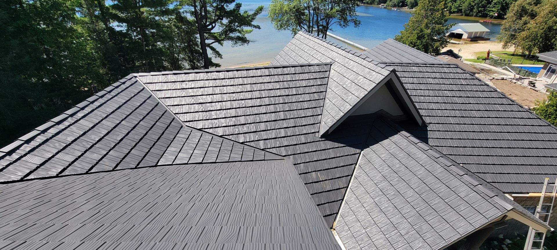 An aerial view of a roof of a house with a lake in the background.