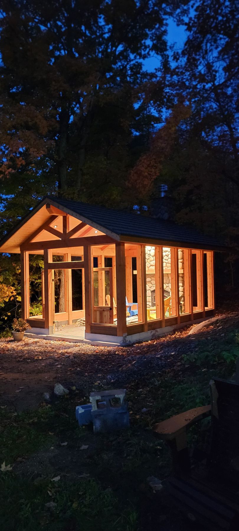 A small wooden house is being built in the woods at night.