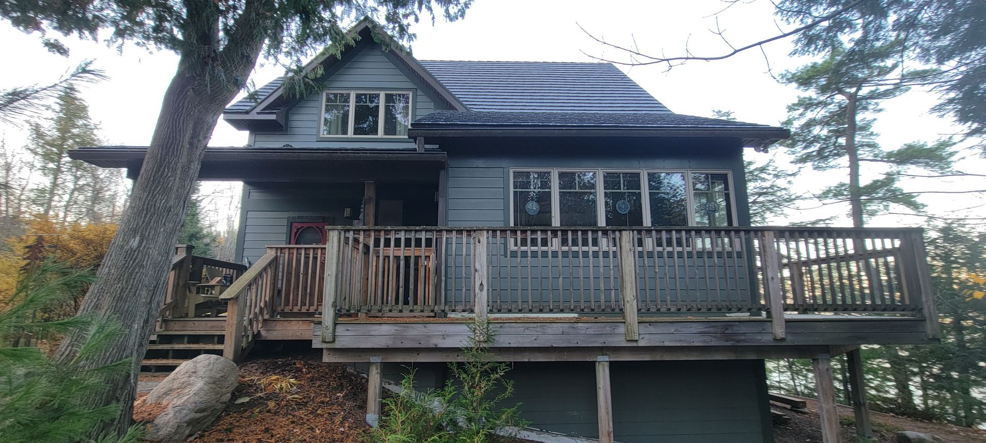 A small house with a large deck is sitting on top of a hill.