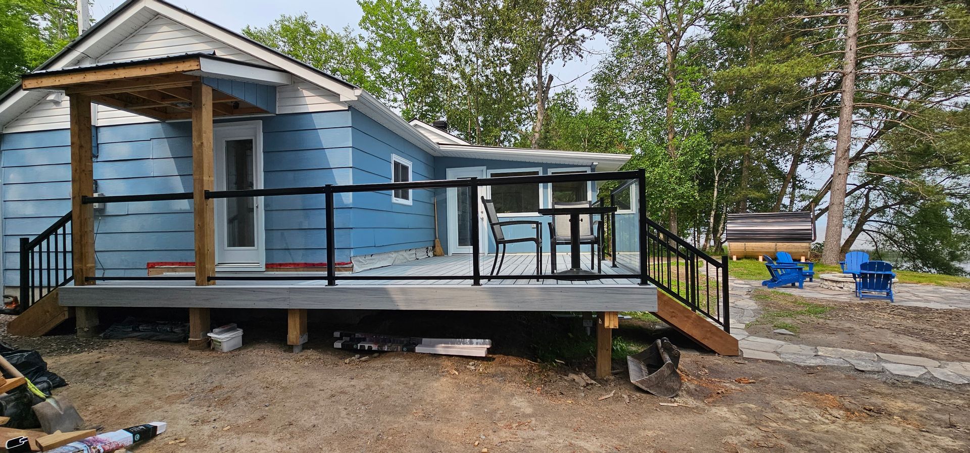 A small blue house with a deck and stairs in front of it.