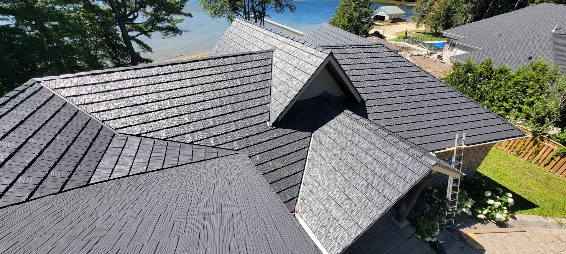 An aerial view of a roof of a house with a lake in the background.
