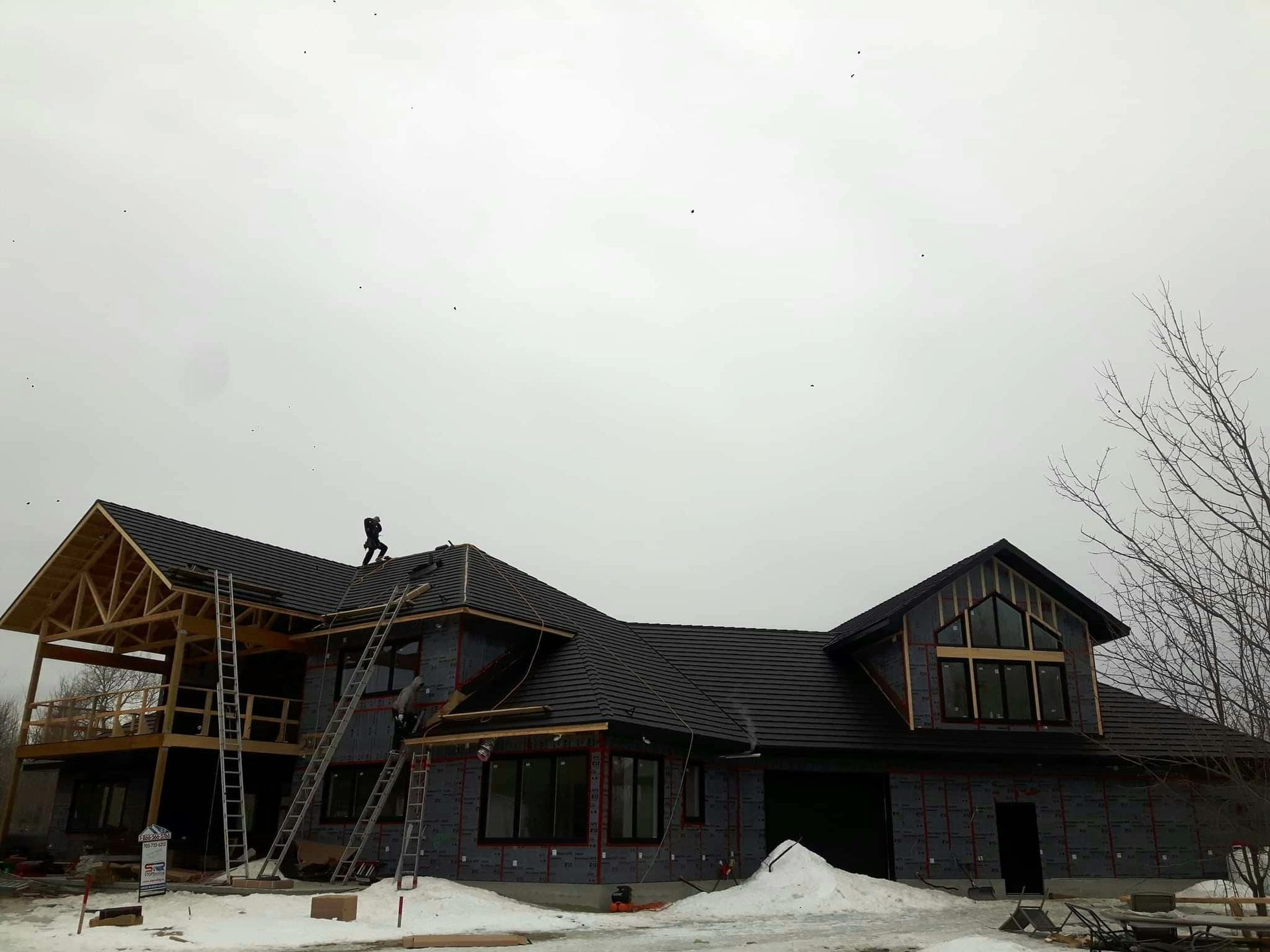 A large house under construction with a man on the roof