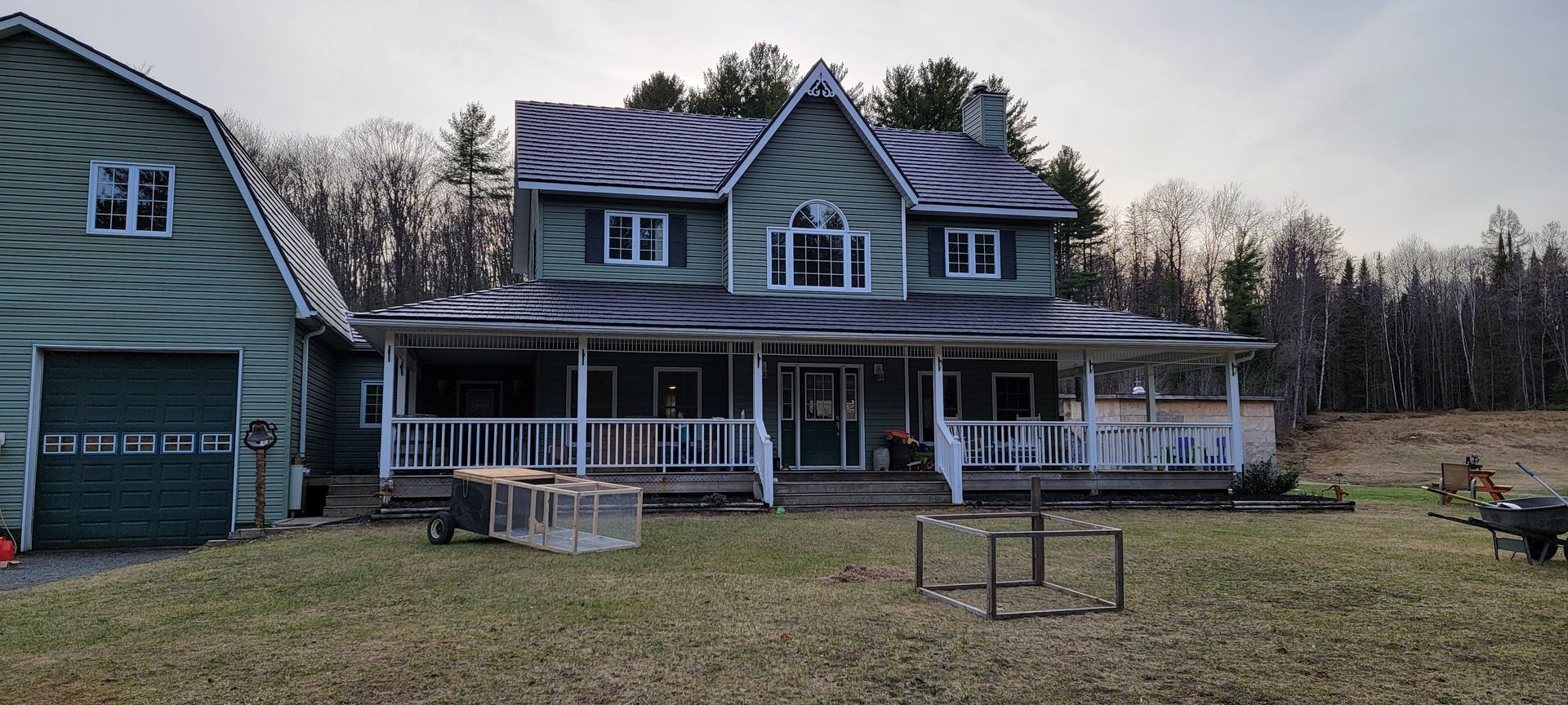 A large green house with a porch and a garage