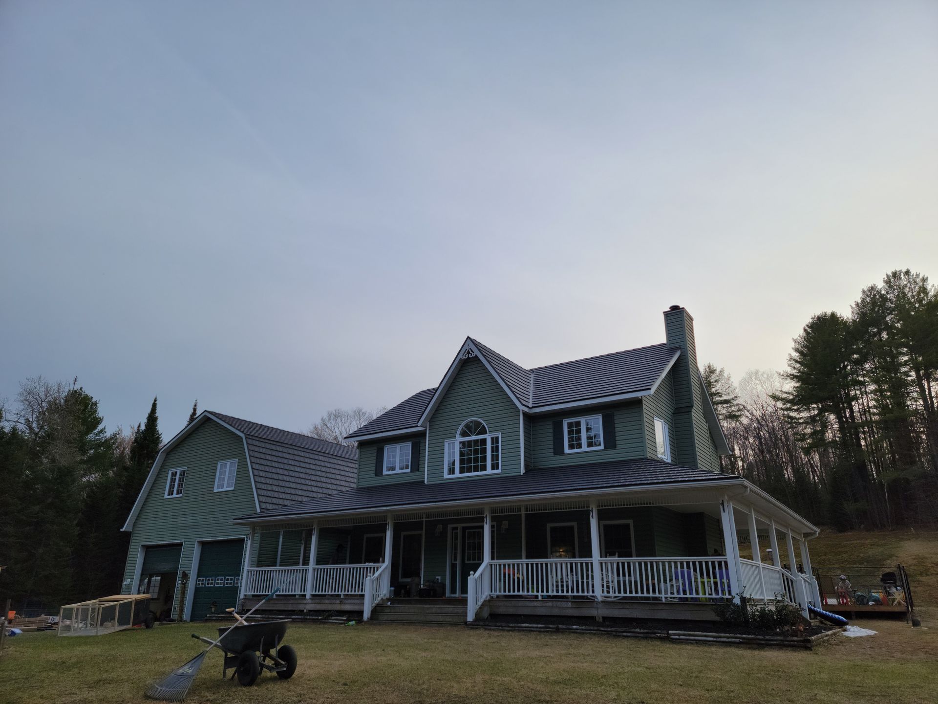 A large house with a large porch and a lawn mower in front of it.