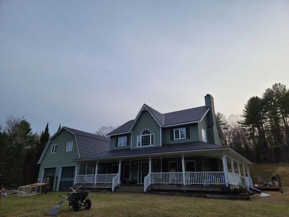 A small house with a large deck is sitting on top of a hill.