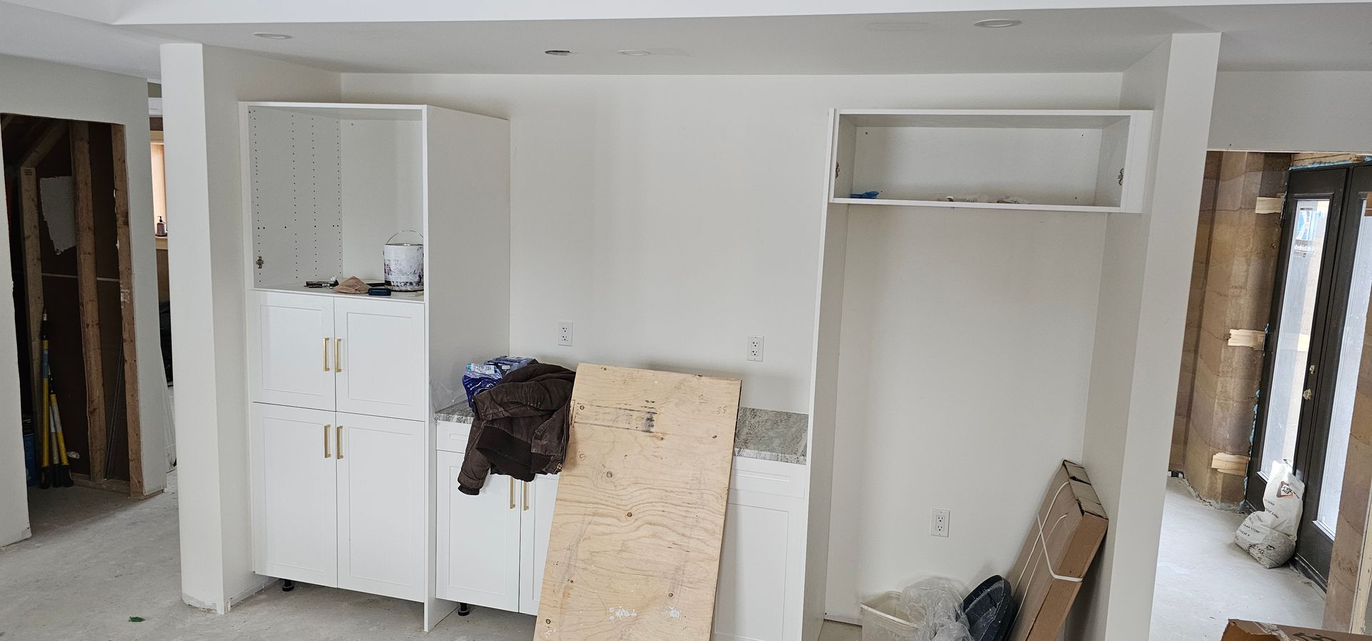 A room with white cabinets and a wooden board on the floor.