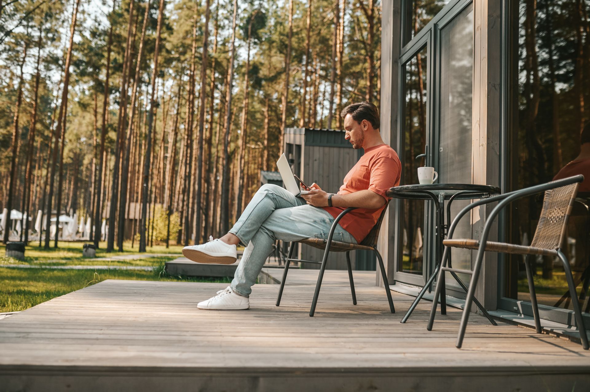 A man is sitting on a porch using a laptop computer.
