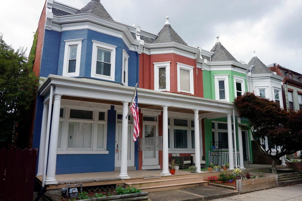 a row of colorful houses with an american flag on the front porch .