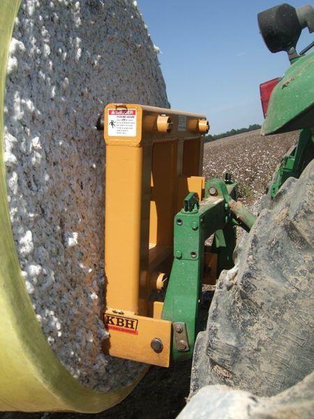 A large roll of cotton is being rolled on a john deere tractor