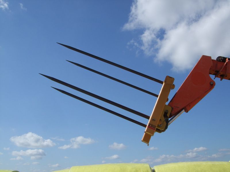 A tractor with a bunch of hay bales in the background