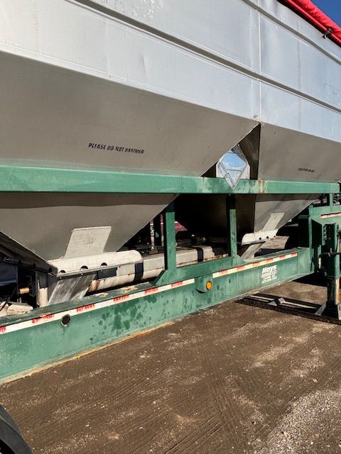 Green and silver grain trailer on a sunny day.