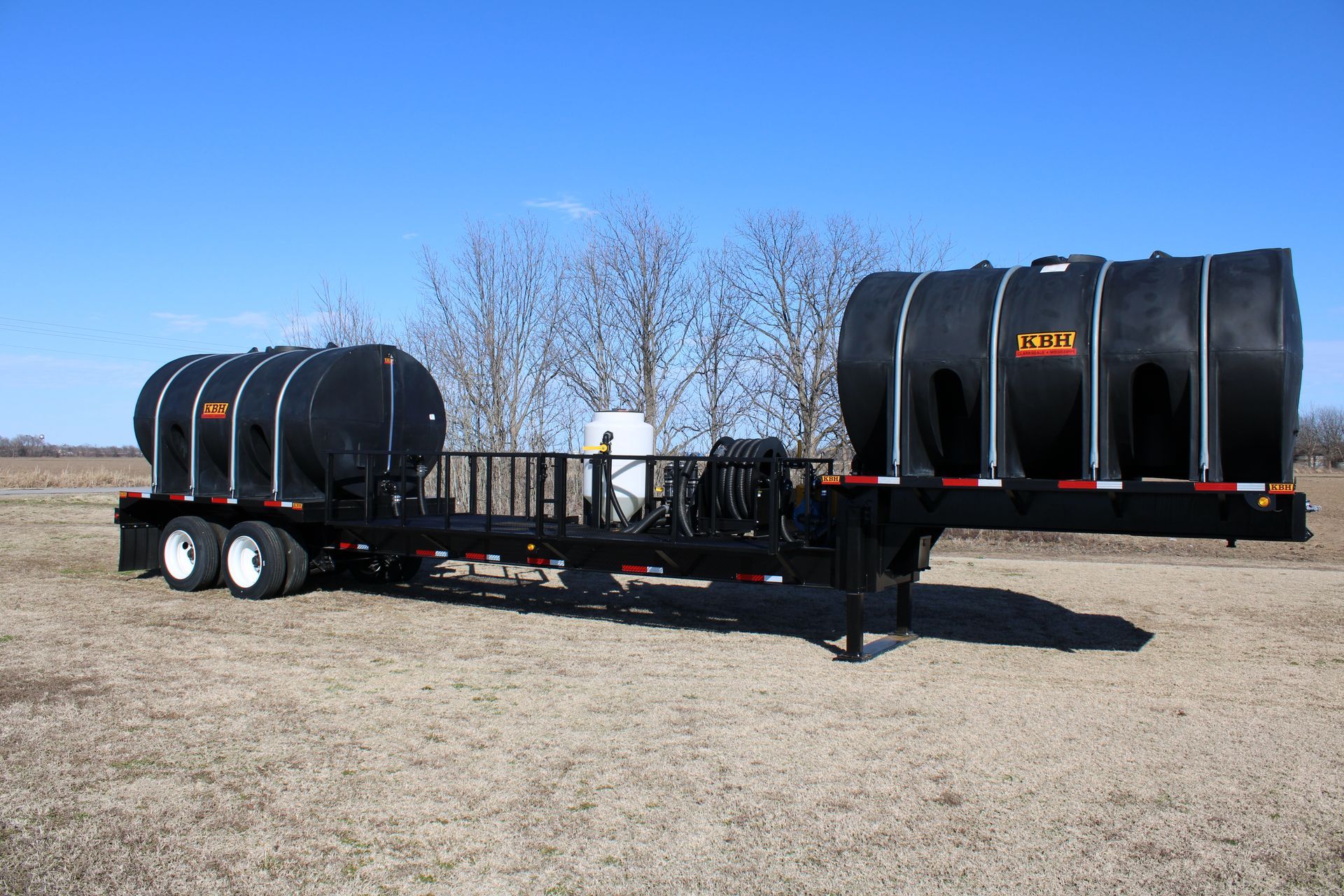 Black tank trailer in a field on a sunny day.