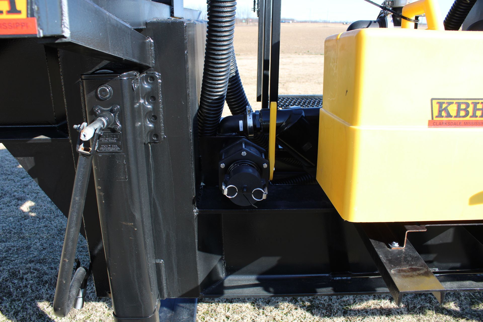 Black equipment frame with a yellow box and a black pump.