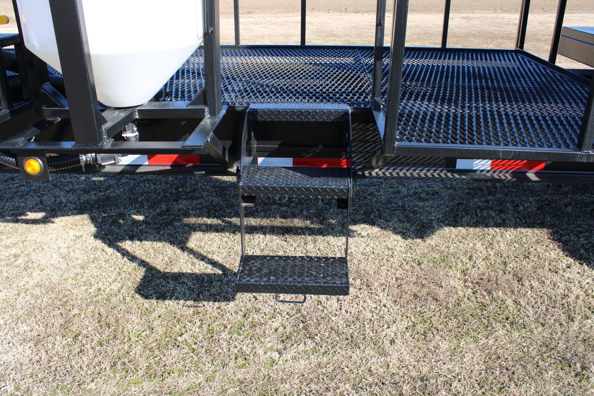Black metal steps leading to a trailer deck, with a white tank visible.
