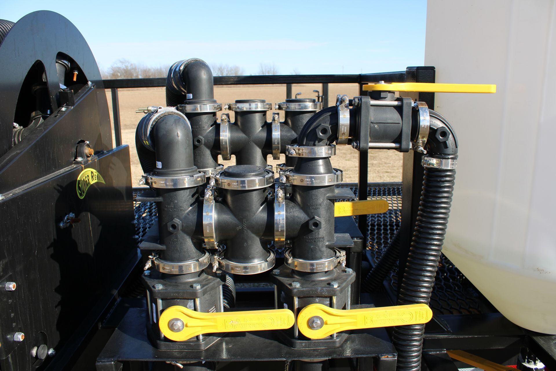 Black pipes and valves with yellow handles on a machine, likely for liquid transfer.
