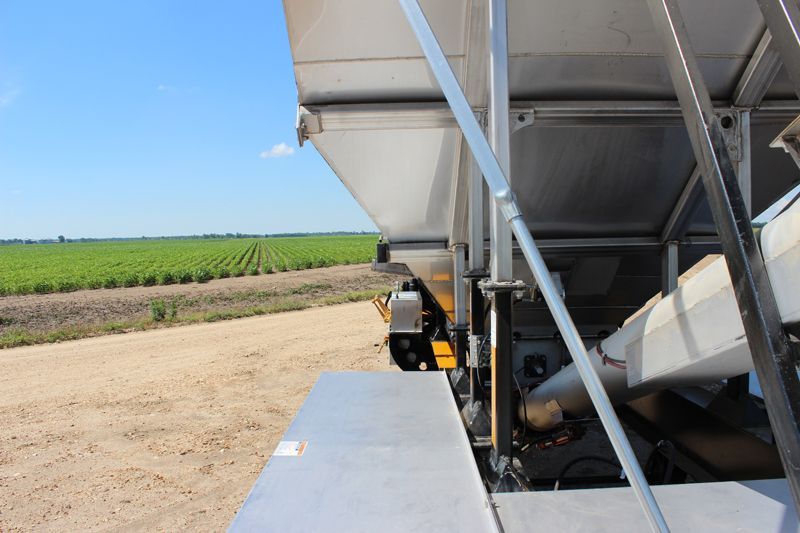 A large white trailer is parked in a dirt field.