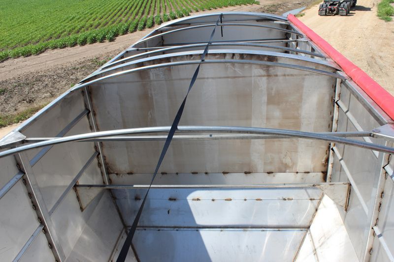 The inside of a stainless steel trailer with a tractor in the background