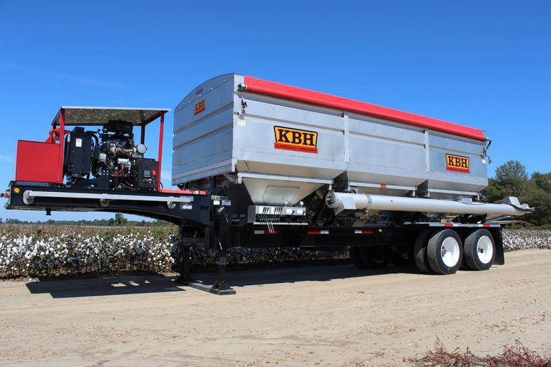 A kbh trailer is parked in a field of cotton