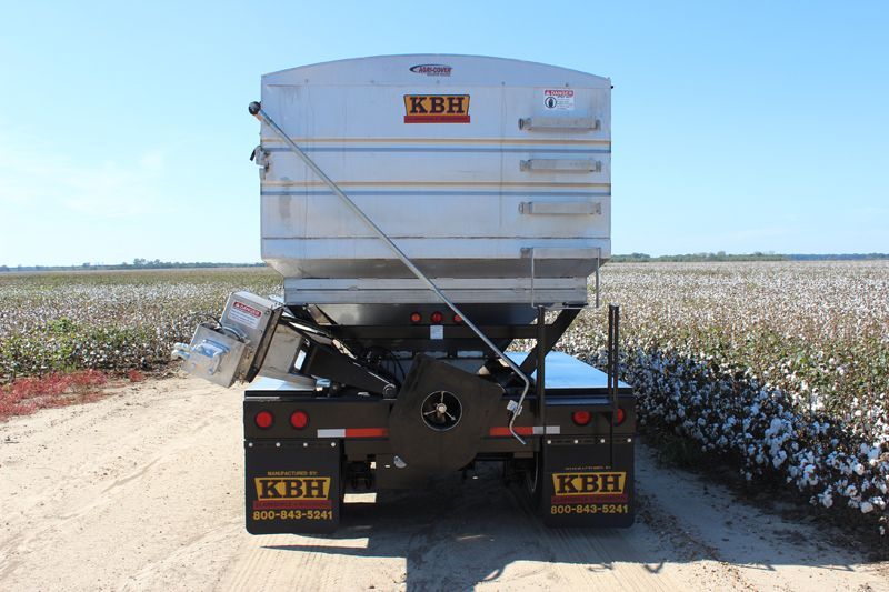 A truck is parked in front of a field of cotton.