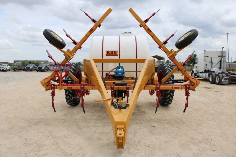 A tractor with a trailer attached to it is parked in a dirt lot.