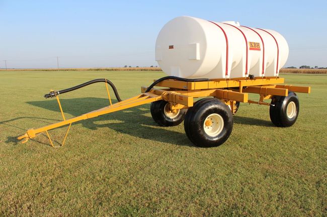 A white tank on a yellow trailer in a grassy field