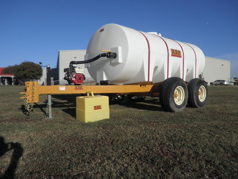 A large white tank is on a trailer in a field