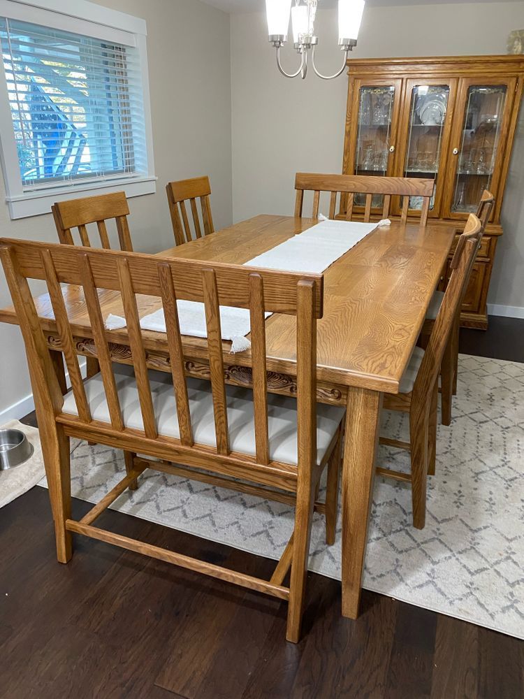 Dining room with a wooden table, chairs, bench, and hutch. A rug lies beneath the furniture.