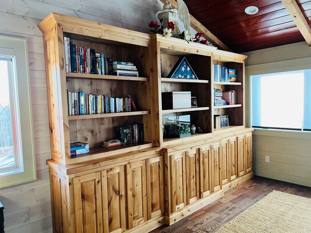 Wooden built-in bookshelf filled with books and decorative items, set against a window and red ceiling.