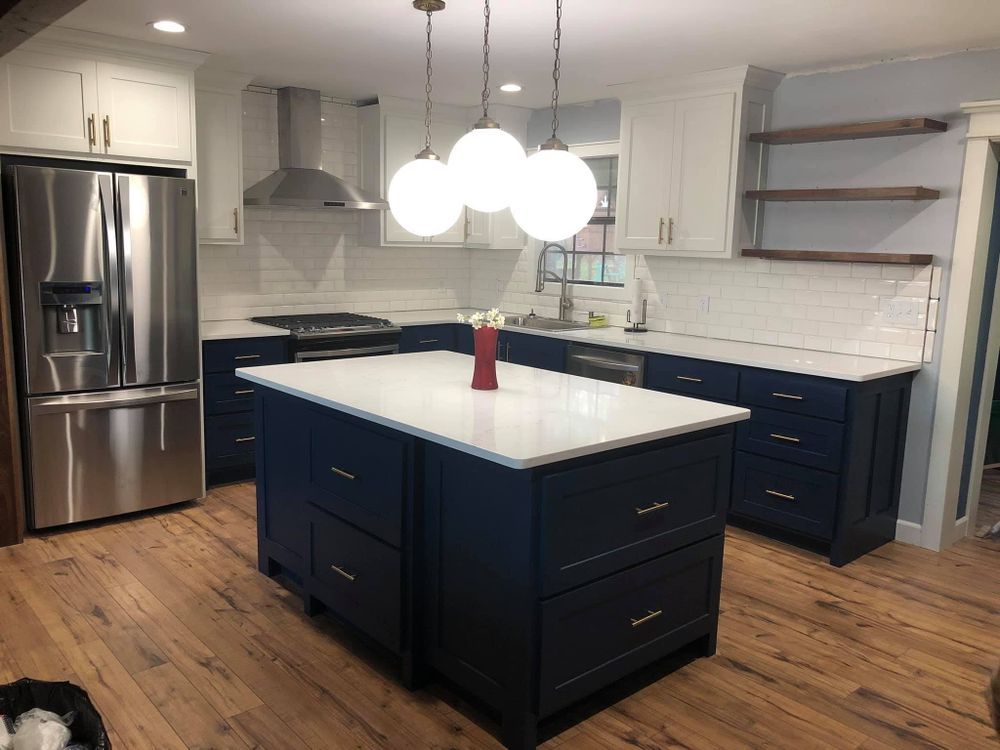 Modern kitchen with blue island and white cabinets, stainless steel appliances, and wood floors.