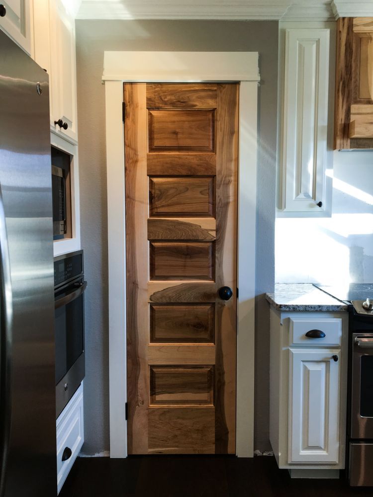Wooden door with rustic texture in a kitchen setting; white trim and cabinets.