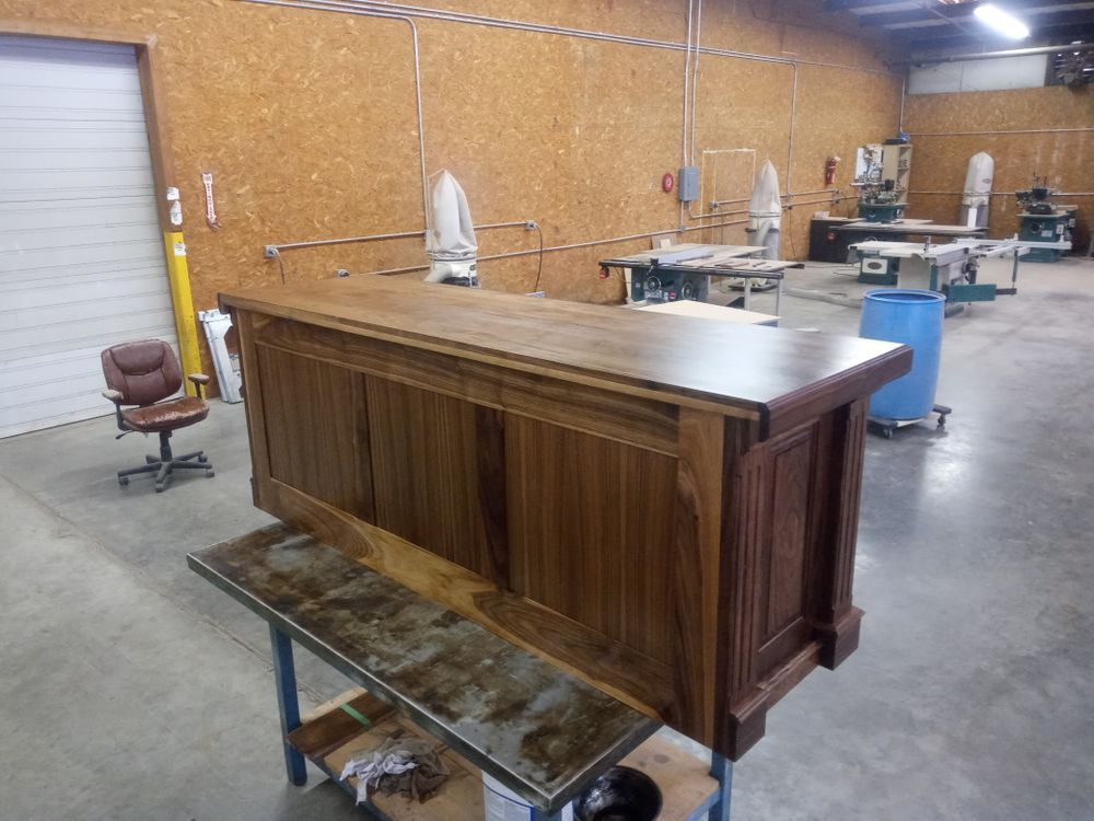Finished wooden bar on a metal table, in a workshop. Brown tones dominate the scene.