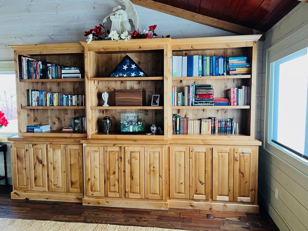 Wooden built-in bookshelf filled with books and decorative items, set against a wood-paneled wall.