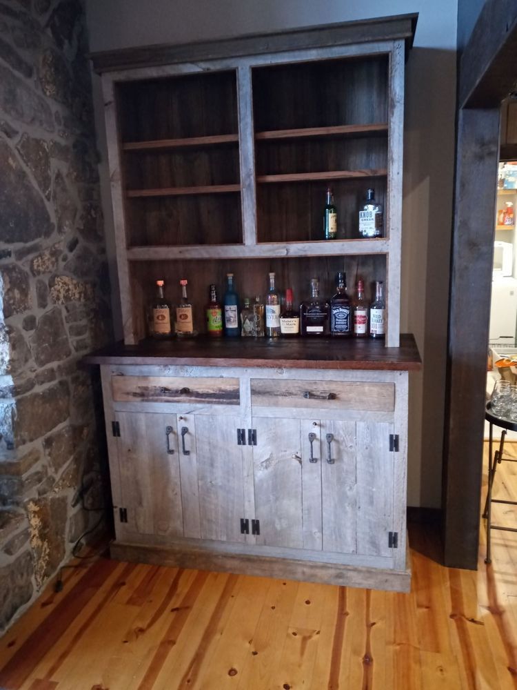 Wooden hutch with open shelves, cabinets, and a counter. Bottles of liquor are displayed on the shelves and counter.
