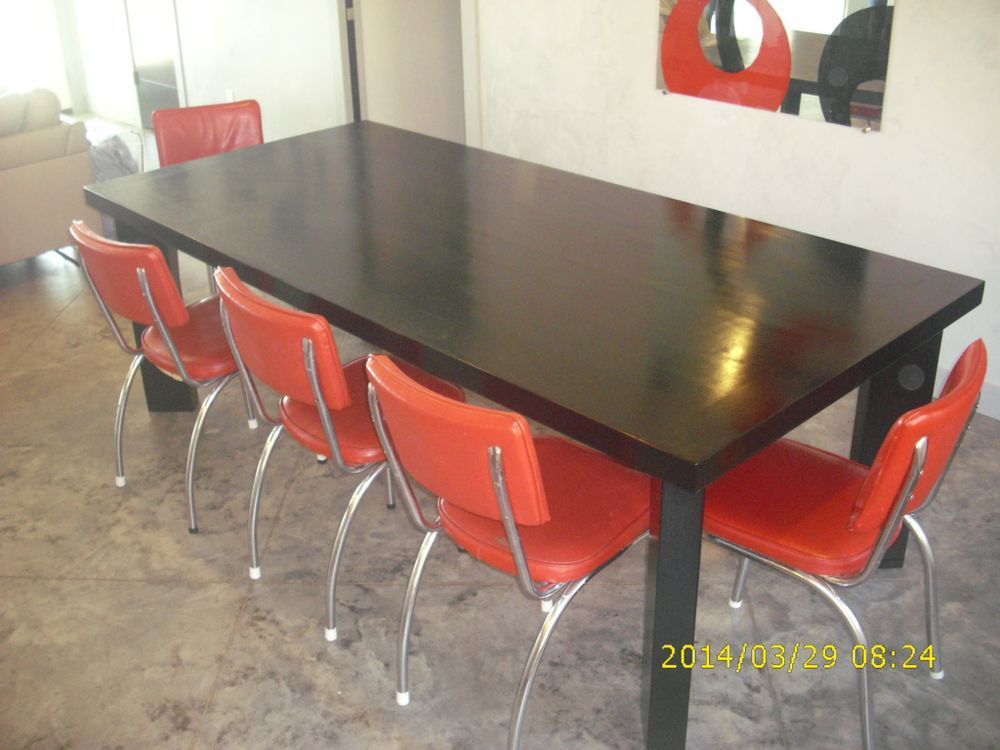 Dark wooden dining table with six red chairs; a modern interior.