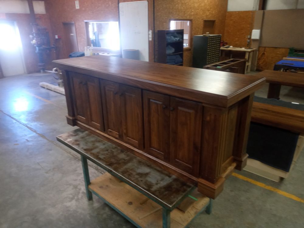 Wooden bar with cabinet doors and countertop, in a workshop setting.