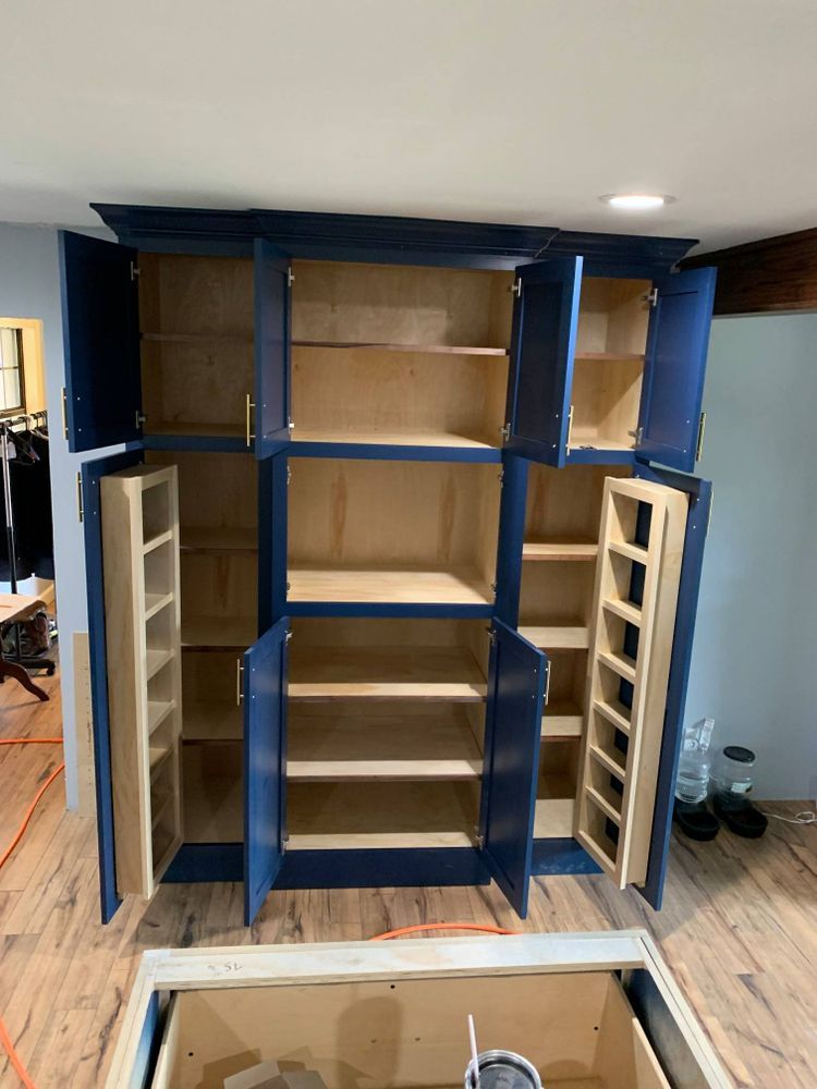 Blue kitchen cabinets, open, showing shelves and interior. Light wood interior.