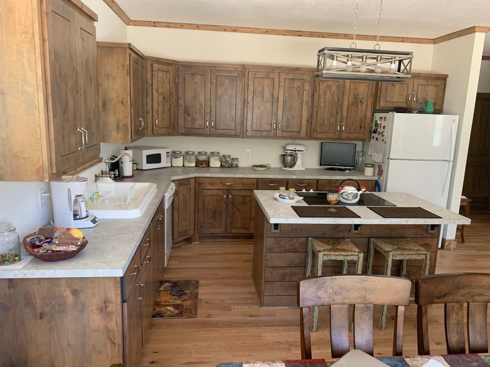 Wooden kitchen with countertops, cabinets, an island, and white appliances.