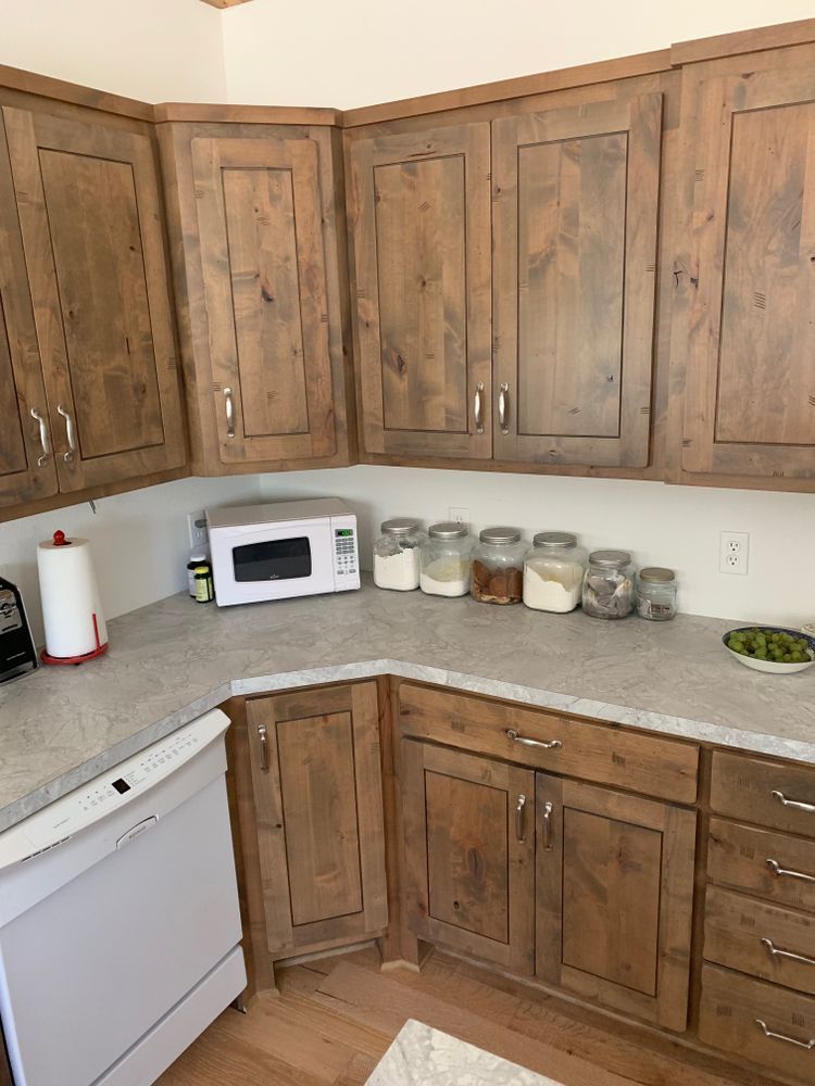 Kitchen with brown wooden cabinets, gray countertops, white appliances, and jars of food.