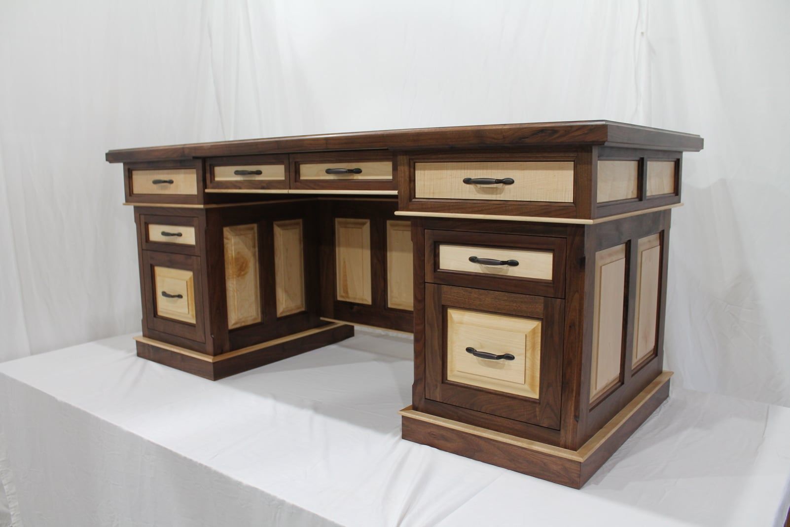 Wooden desk with dark brown and light wood sections, drawers, and a boxy design.