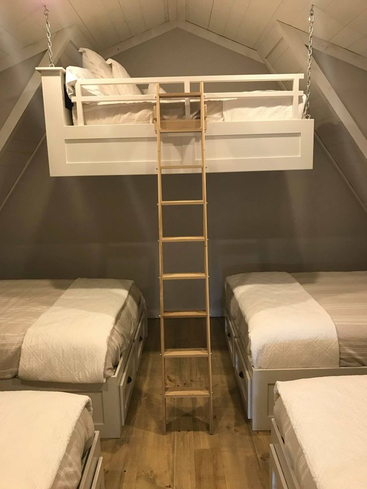 Bedroom with a hanging bunk bed and three beds below, light wood ladder.
