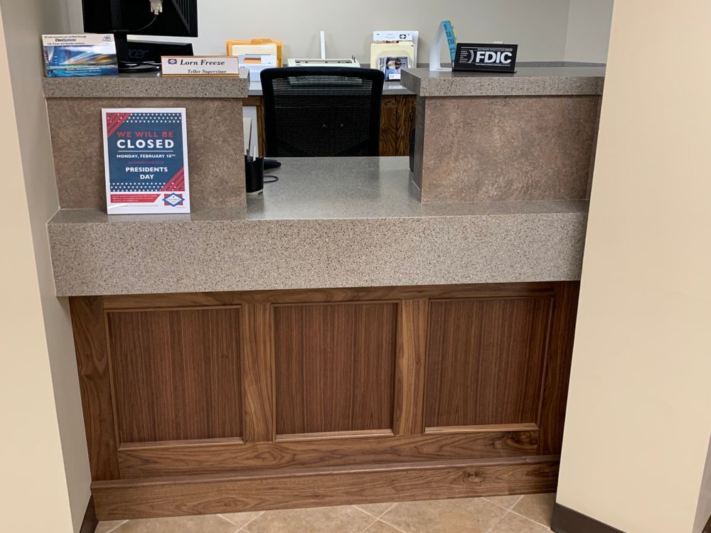 Bank counter, closed sign displayed. Wooden paneling below, speckled countertop.