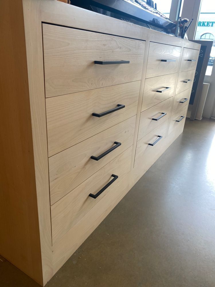 Light wood dresser with black drawer pulls, in a well-lit room.