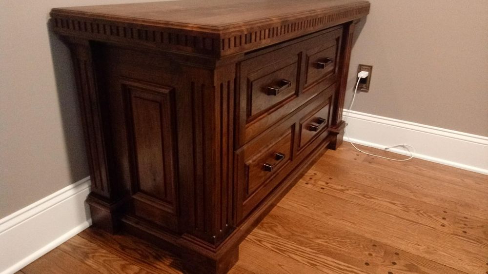 Dark wooden nightstand with drawers in a room.