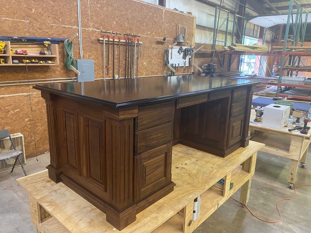 Wooden executive desk in a workshop, dark finish, on a wooden workbench.