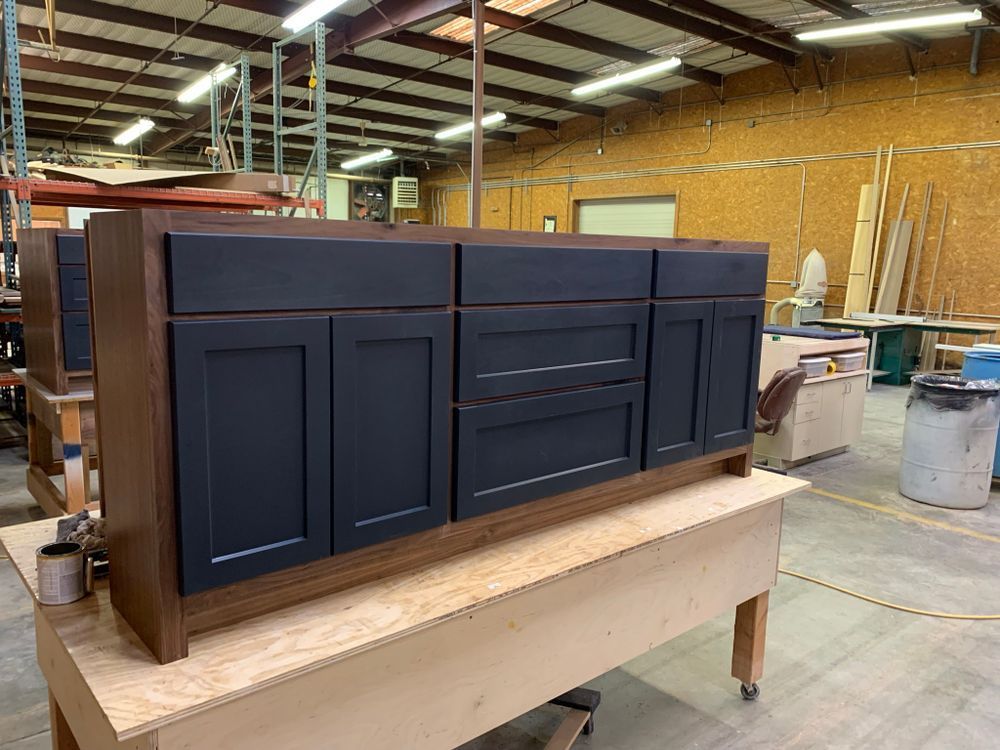 Dark blue and wood bathroom vanity on a work table in a workshop.