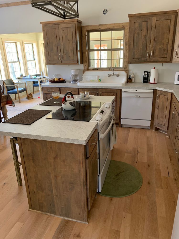 Rustic kitchen with wood cabinets, island, and appliances, including a range and dishwasher.