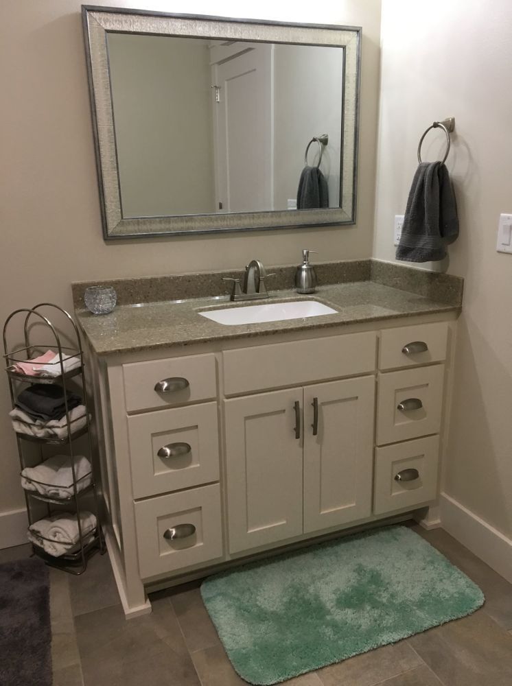 Bathroom with white vanity, gray countertop, mirror, gray towels, and a teal bath mat.