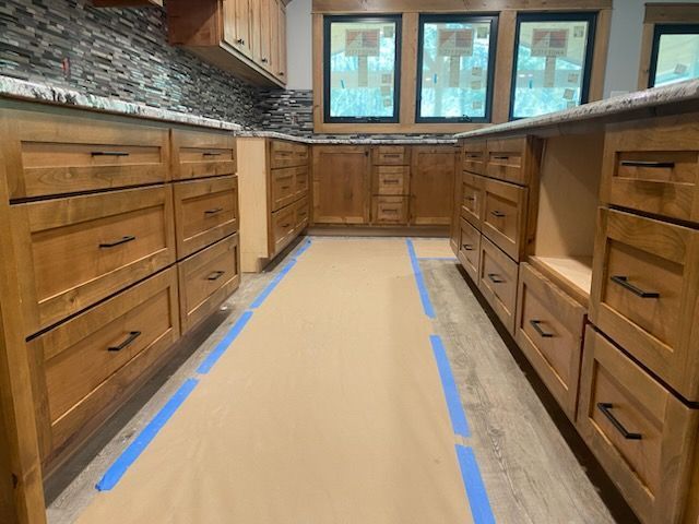Kitchen with light-brown cabinets, granite countertops, and protective paper on the floor.