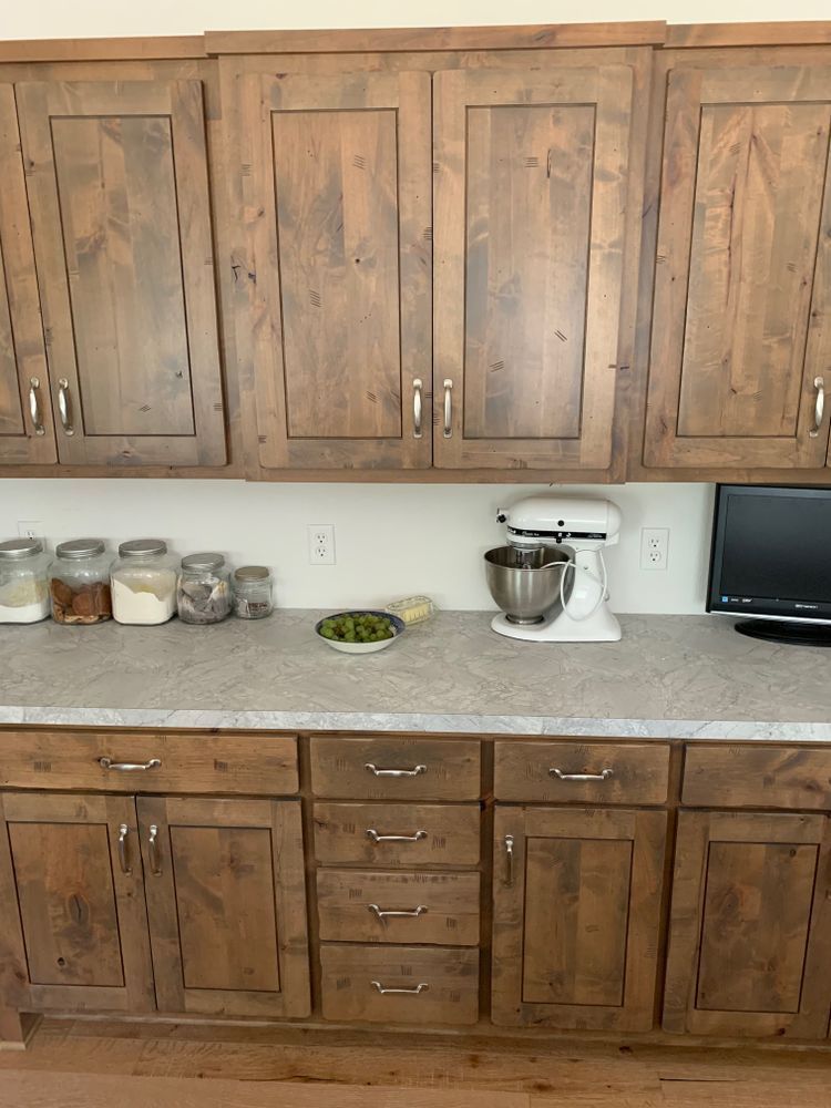 Wooden kitchen cabinets and countertop with jars, mixer, and food items.
